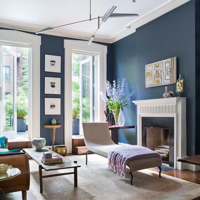 Large transitional open concept medium tone wood floor living room library photo in New York with blue walls, a standard fireplace and no tv