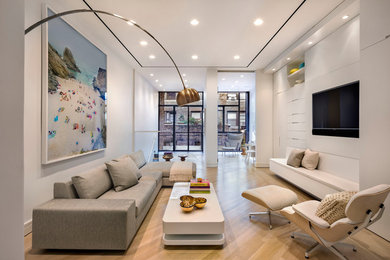 Diseño de salón abierto contemporáneo con paredes blancas, suelo de madera clara y televisor colgado en la pared