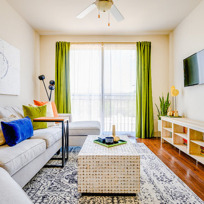 Example of a small trendy open concept medium tone wood floor and brown floor living room library design in Dallas with beige walls, no fireplace and a wall-mounted tv