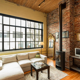 Living room - mid-sized industrial open concept medium tone wood floor living room idea in Seattle with yellow walls, a wood stove and a tv stand