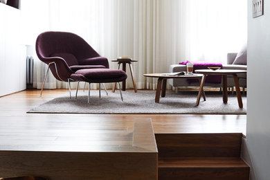 Modelo de salón tipo loft minimalista de tamaño medio sin chimenea con suelo de madera en tonos medios, suelo marrón y paredes blancas