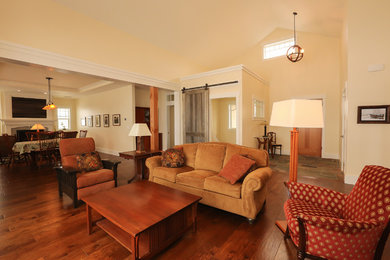 Imagen de salón abierto de estilo americano con suelo de madera en tonos medios, paredes amarillas y todas las chimeneas
