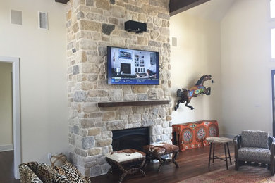 Réalisation d'un grand salon design ouvert avec un mur beige, parquet foncé, une cheminée standard, un manteau de cheminée en pierre et un téléviseur fixé au mur.