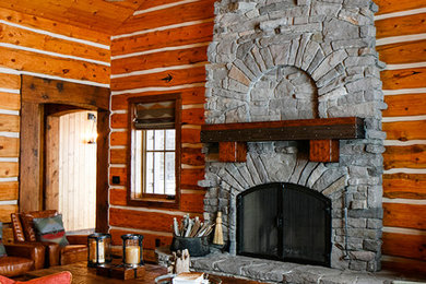 他の地域にあるラグジュアリーな広いラスティックスタイルのおしゃれなLDK (茶色い壁、濃色無垢フローリング、標準型暖炉、石材の暖炉まわり) の写真