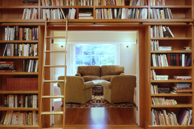 Immagine di un soggiorno american style con libreria e parquet chiaro