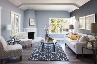 Transitional medium tone wood floor living room photo in Tampa with blue walls, a standard fireplace and no tv