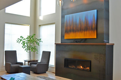 Diseño de salón contemporáneo con suelo de madera clara, marco de chimenea de metal y televisor retractable