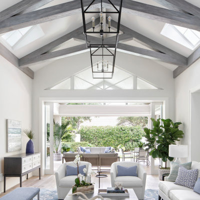 Example of a large beach style open concept light wood floor and beige floor living room design in Miami with gray walls, no fireplace and a wall-mounted tv