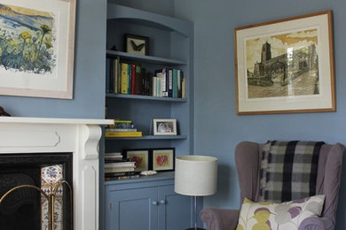 Imagen de biblioteca en casa cerrada de estilo de casa de campo con paredes azules y marco de chimenea de madera