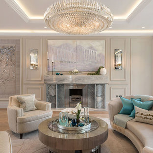 Photo of an expansive classic enclosed living room in London with a concealed tv, beige walls, light hardwood flooring, a standard fireplace, a stone fireplace surround and beige floors.