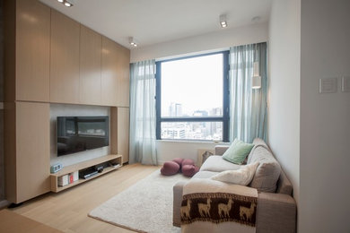 Ejemplo de salón cerrado minimalista de tamaño medio con paredes grises, suelo de madera en tonos medios y televisor colgado en la pared
