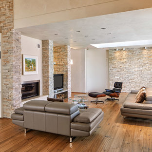 Idee per un soggiorno minimal con pareti beige, pavimento in legno massello medio, camino classico, TV autoportante e pavimento marrone