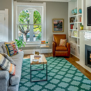 Mittelgroßes, Offenes Modernes Wohnzimmer mit grauer Wandfarbe, dunklem Holzboden, Kamin, gefliester Kaminumrandung, Wand-TV und braunem Boden in Denver
