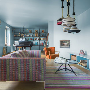 Design ideas for a large bohemian open plan living room in London with blue walls, light hardwood flooring, beige floors, a corner fireplace, a plastered fireplace surround and a wall mounted tv.
