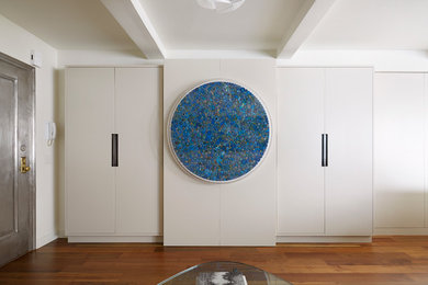 Immagine di un piccolo soggiorno design aperto con pareti bianche, pavimento in legno massello medio e TV nascosta