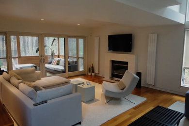 Living room in Boston with beige walls, medium hardwood flooring and a wall mounted tv.