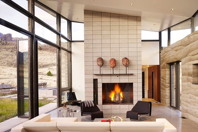 他の地域にある広いコンテンポラリースタイルのおしゃれなLDK (コンクリートの床、標準型暖炉、ベージュの壁、コンクリートの暖炉まわり、テレビなし) の写真