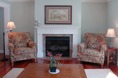 Classic formal enclosed living room in Minneapolis with blue walls, medium hardwood flooring, a standard fireplace, a plastered fireplace surround and no tv.