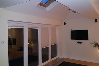 This is an example of a medium sized modern formal enclosed living room in West Midlands with beige walls, light hardwood flooring and a wall mounted tv.