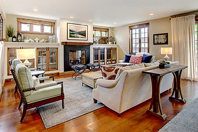 This is an example of a large traditional open plan living room in Denver with beige walls, medium hardwood flooring, a standard fireplace, a metal fireplace surround and a concealed tv.