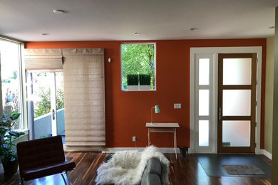 デンバーにある中くらいなトランジショナルスタイルのおしゃれなリビング (オレンジの壁、濃色無垢フローリング、暖炉なし、テレビなし、茶色い床) の写真
