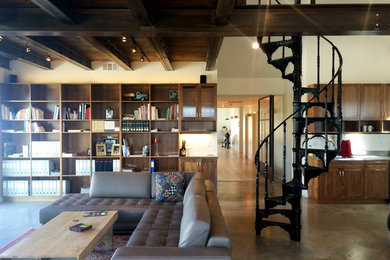 Modelo de biblioteca en casa abierta de tamaño medio sin chimenea y televisor con paredes beige y suelo de cemento