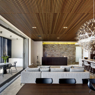 Foto de salón abierto, contemporáneo, de tamaño medio, sin chimenea, con paredes blancas, suelo de cemento y televisor retractable