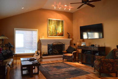 Example of a mid-sized transitional open concept medium tone wood floor living room design in Seattle with a music area, orange walls, a standard fireplace, a stone fireplace and a wall-mounted tv