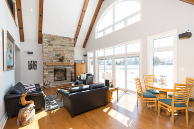 Inspiration for a mid-sized craftsman formal and open concept medium tone wood floor and brown floor living room remodel in Toronto with white walls, a standard fireplace, a stone fireplace and no tv