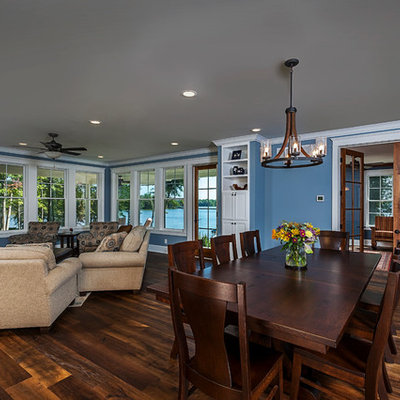 Example of a mid-sized farmhouse open concept medium tone wood floor and brown floor living room design in Other with blue walls, a standard fireplace, a stone fireplace and a wall-mounted tv