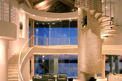 Ejemplo de salón tipo loft contemporáneo de tamaño medio con paredes beige, suelo de travertino, chimenea de doble cara y marco de chimenea de piedra