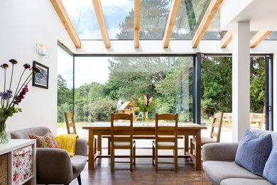 Diseño de salón abierto contemporáneo de tamaño medio sin chimenea y televisor con paredes blancas, suelo de madera en tonos medios y suelo marrón