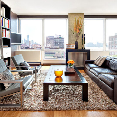 Example of a mid-sized minimalist open concept medium tone wood floor living room library design in New York with gray walls, a standard fireplace, a metal fireplace and a wall-mounted tv