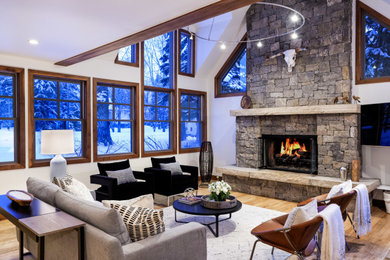 デンバーにあるラスティックスタイルのおしゃれなLDK (白い壁、無垢フローリング、標準型暖炉、石材の暖炉まわり、茶色い床、三角天井) の写真