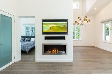 Example of a mid-sized trendy open concept medium tone wood floor and gray floor living room design in Los Angeles with white walls, a hanging fireplace, a plaster fireplace and a media wall