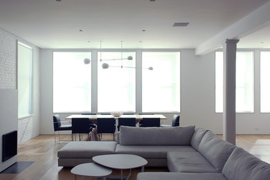 Large minimalist loft-style living room photo in New York with white walls, a wall-mounted tv and a wood stove