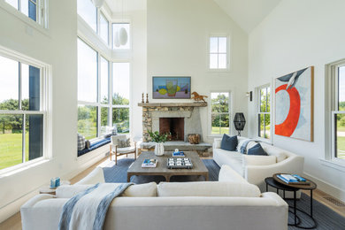 Inspiration for a coastal light wood floor, beige floor and vaulted ceiling living room remodel in Boston with white walls, a standard fireplace, a stone fireplace and a wall-mounted tv