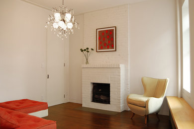 Example of a small trendy dark wood floor living room design in New York with white walls, a standard fireplace, a brick fireplace and no tv