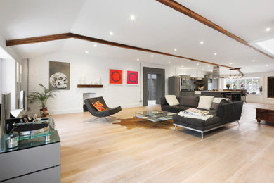 Diseño de salón abierto clásico renovado con paredes blancas, suelo de madera clara, marco de chimenea de ladrillo y suelo beige