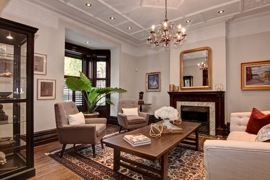 Example of a mid-sized classic formal and enclosed medium tone wood floor living room design in Montreal with beige walls, a standard fireplace, a wood fireplace surround and no tv