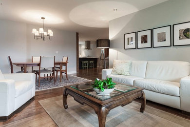 Example of a mid-sized transitional open concept medium tone wood floor living room design in Vancouver with gray walls, a standard fireplace and no tv