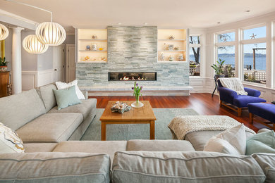 Example of a large beach style open concept medium tone wood floor and brown floor living room design in Seattle with white walls, a standard fireplace, a stone fireplace and no tv