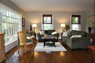 Example of a mid-sized classic enclosed medium tone wood floor living room design in Milwaukee with gray walls, a standard fireplace, a wood fireplace surround and a tv stand