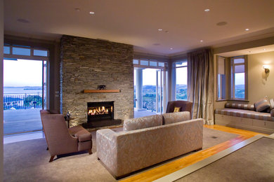オークランドにある高級な広いコンテンポラリースタイルのおしゃれなLDK (グレーの壁、カーペット敷き、標準型暖炉、石材の暖炉まわり、グレーの床) の写真