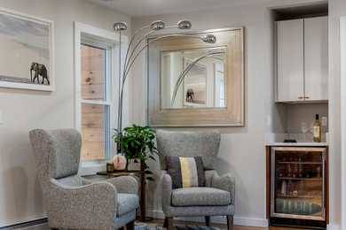 Foto de salón con barra de bar abierto clásico renovado grande con paredes grises y suelo de madera en tonos medios
