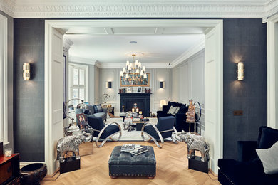 ロンドンにある中くらいなトラディショナルスタイルのおしゃれな独立型リビング (グレーの壁、淡色無垢フローリング、標準型暖炉、金属の暖炉まわり、ベージュの床、黒いソファ) の写真