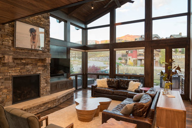 Design ideas for a medium sized contemporary open plan living room in Denver with a standard fireplace, a stone fireplace surround, a wall mounted tv and brown floors.