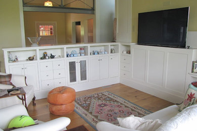 Imagen de salón abierto tradicional renovado grande sin chimenea con televisor retractable, paredes amarillas y suelo de madera clara