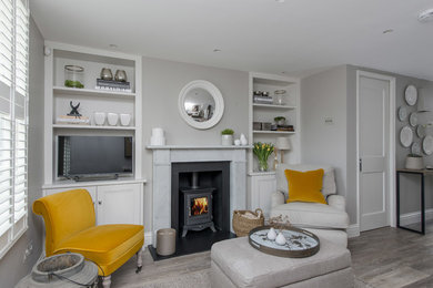 Modernes Wohnzimmer mit Laminat, Kaminofen, Kaminumrandung aus Stein und freistehendem TV in London