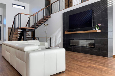 Diseño de salón tipo loft minimalista grande con paredes blancas, suelo de madera en tonos medios, todas las chimeneas, marco de chimenea de baldosas y/o azulejos, televisor colgado en la pared y suelo marrón